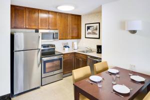 a kitchen with a table and a stainless steel refrigerator at Residence Inn Milford in Milford