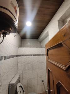 a bathroom with a toilet and a ceiling with a light at Mehdudia Guest House in Shimla