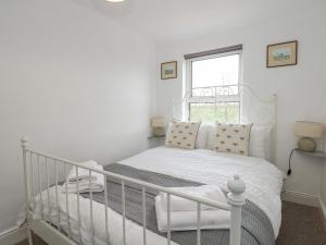 a white bedroom with a white bed and a window at Fieldview Cottage in Great Massingham