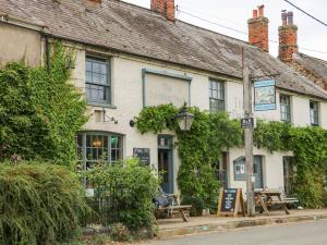 a white building with a sign in front of it at Fieldview Cottage in Great Massingham