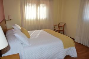 a bedroom with a large white bed with a window at Hotel Restaurante Val in Antas de Ulla