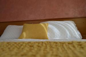 1 cama con 2 almohadas blancas y almohada amarilla en Hotel Restaurante Val en Antas de Ulla
