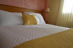 uma cama grande com lençóis brancos e almofadas amarelas em Hotel Restaurante Val em Antas de Ulla