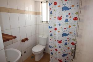 a bathroom with a toilet and a shower curtain with fishes at Villa Sol e Mar - Vila do Maio - Ponta Preta in Vila do Maio