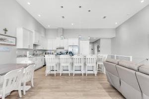 a white kitchen with white chairs and a table at Pelican at Sound Side in Fort Walton Beach