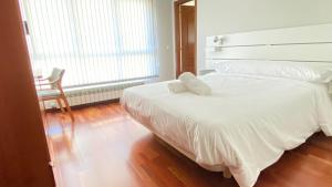 1 cama blanca con 2 almohadas en el dormitorio en Apartamentos Pantón Ribeira Sacra, en Ferreira