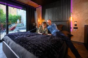 a man and a woman sitting on a bed at Spa Maroilles in Maroilles
