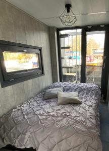 uma cama com almofadas num quarto com uma janela em Unique Water Stay Tiny Hausboot für 2 Personen em Zehdenick