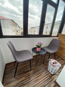 2 stoelen en een tafel in een kamer met ramen bij Apartament EXCLUSIVE Târgu Ocna in Tîrgu Ocna
