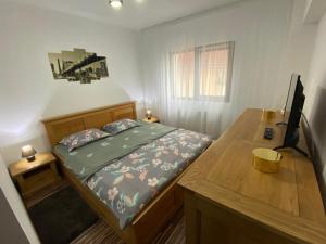 een kleine slaapkamer met een bed en een houten bureau bij Apartament EXCLUSIVE Târgu Ocna in Tîrgu Ocna
