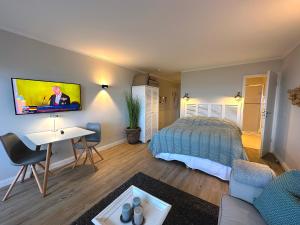 a bedroom with a bed and a desk and a tv at KNYD'S am MEER in Wenningstedt