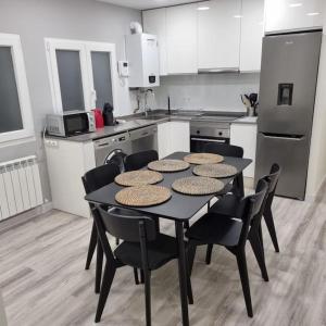 a kitchen with a black table with chairs and a kitchen with a refrigerator at Soho Boutique Tioda, Totalmente reformado junto a las estaciones, WIFI in Oviedo