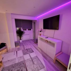 ein Wohnzimmer mit violetter Beleuchtung und einem TV in der Unterkunft Soho Boutique Tioda, Totalmente reformado junto a las estaciones, WIFI in Oviedo
