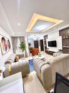 a living room with couches and a flat screen tv at Bee-City Homes in Abuja