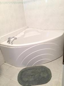 eine weiße Badewanne im Bad mit grünem Teppich in der Unterkunft Apartamento City in Košice