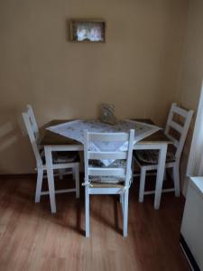 a white dining room table with four chairs and a painting at Ferienhaus Rodewald in Bomlitz