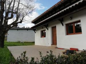 ein weißes Haus mit einer Holztür im Hof in der Unterkunft Casa de campo entre dos parques naturales in Igorre