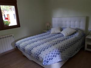 Un dormitorio con una cama azul y blanca y una ventana en Casa de campo entre dos parques naturales, en Igorre