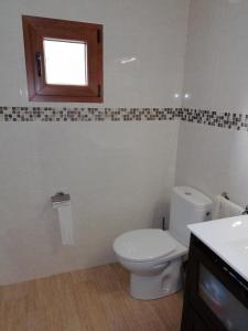 een badkamer met een wit toilet en een raam bij Casa de campo entre dos parques naturales in Igorre