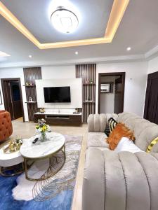 a living room with a couch and a tv at Bee-City Homes in Abuja