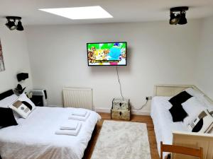 Goodnestone的住宿－Canterbury romantic modern home，一间卧室设有两张床,墙上配有电视。