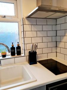 eine Küchentheke mit einem Waschbecken und einem Fenster in der Unterkunft Canterbury romantic modern home in Goodnestone