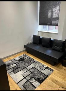 a black couch in a living room with a rug at Modern flat in Maidstone in Kent