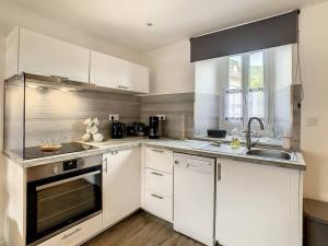 a kitchen with white cabinets and a sink at Happy HOME in Cierp