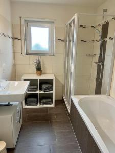 La salle de bains est pourvue d'une baignoire, d'un lavabo et d'une douche. dans l'établissement Ferienwohnungen Verma, à Schwanau