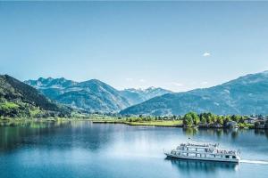 um barco num lago com montanhas ao fundo em Chalet Molly by we rent em Zell am See