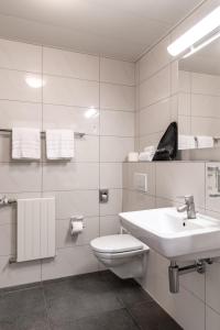 La salle de bains blanche est pourvue de toilettes et d'un lavabo. dans l'établissement Hotel Sursee, à Sursee