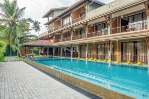 a hotel with a swimming pool in front of a building at Anura's Elephant in Beruwala