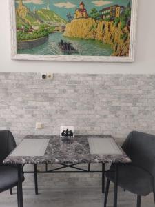 a table with two chairs and a painting on the wall at AhmashenebeliApart in Tbilisi City