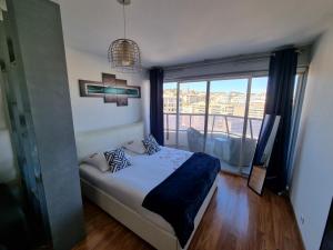 a bedroom with a bed and a large window at Appartement T1 Marseille Prado Chanot Plage in Marseille