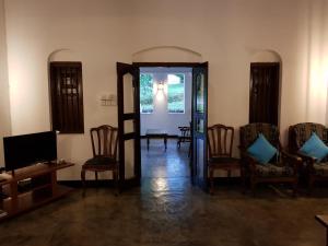 ベントータにあるチトラ アーユルヴェーダのドア、椅子、テレビが備わる客室です。