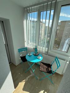 a blue table and chairs in a room with windows at Nicola Flat Mall in Arad