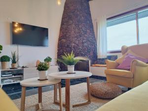 a living room with two tables and a stone fireplace at House Experience Villa Violeta in La Victoria de Acentejo