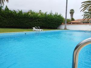 uma grande piscina azul com duas cadeiras em House Experience Villa Violeta em La Victoria de Acentejo