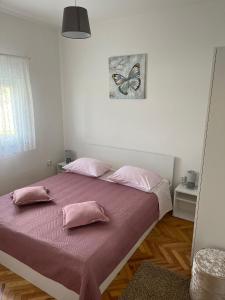 um quarto com uma cama com almofadas cor-de-rosa e uma fotografia de borboleta em Apartment Sanja em Zadar