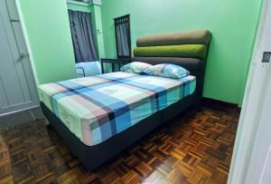 een slaapkamer met een bed met een geruite deken bij 3 Rooms 2 parking 10pax PSR Comfy Sofa&Bed near MRT Eateries McD in Seri Kembangan