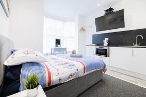 ein Schlafzimmer mit einem Bett und eine Küche mit einem Waschbecken in der Unterkunft Hillcrest Studio Apartments in Cleethorpes