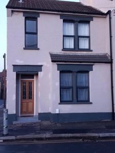 a white house with a brown door on a street at Luxury holiday home, near beach in Southend-on-Sea