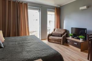 a bedroom with a bed and a chair and a television at VacationClub - Bryza 7 Apartament 5 in Świnoujście