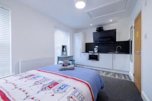 a white bedroom with a bed and a kitchen at Hillcrest Studio Apartments in Cleethorpes