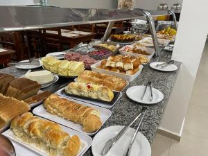 a buffet with many different types of bread and pastries at Pousada Monte Oliveira in Aparecida