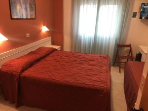 a bedroom with a red bed and a window at Hotel Regina in Lido di Camaiore