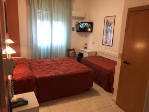 una camera d'albergo con due letti e una televisione di Hotel Regina a Lido di Camaiore