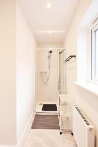a white bathroom with a shower with a glass door at Sea side family rest and holiday in Colwyn Bay