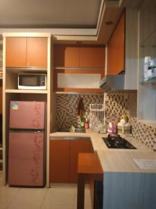 a kitchen with brown cabinets and a pink refrigerator at Tifolia Apartment Pulomas - Kelapa Gading in Jakarta