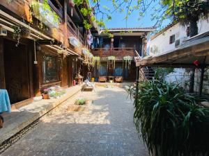 un cortile di un vecchio edificio con piante e panchine di Lewo Guest House a Lijiang